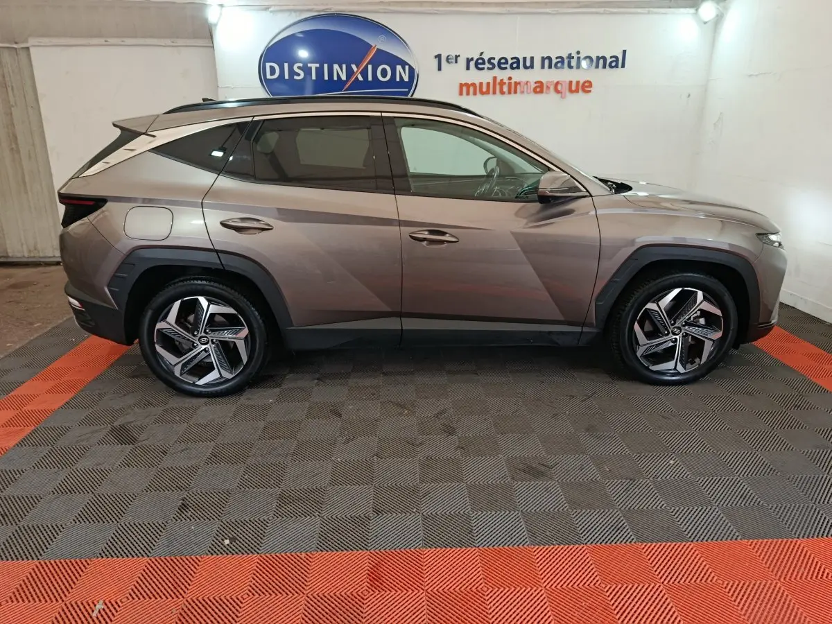 Vue de profil côté gauche du Hyundai Tucson marron 2022 hybride rechargeable dans un showroom intérieur.