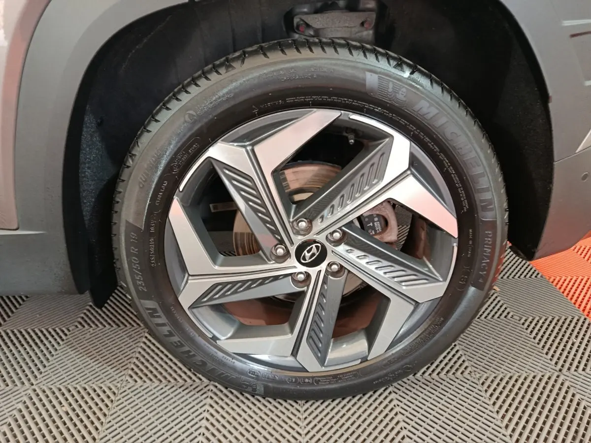 Gros plan sur la roue avant droite marron du Hyundai Tucson 1.6 PHEV 265 HTRAC avec jante alliage distinctive.