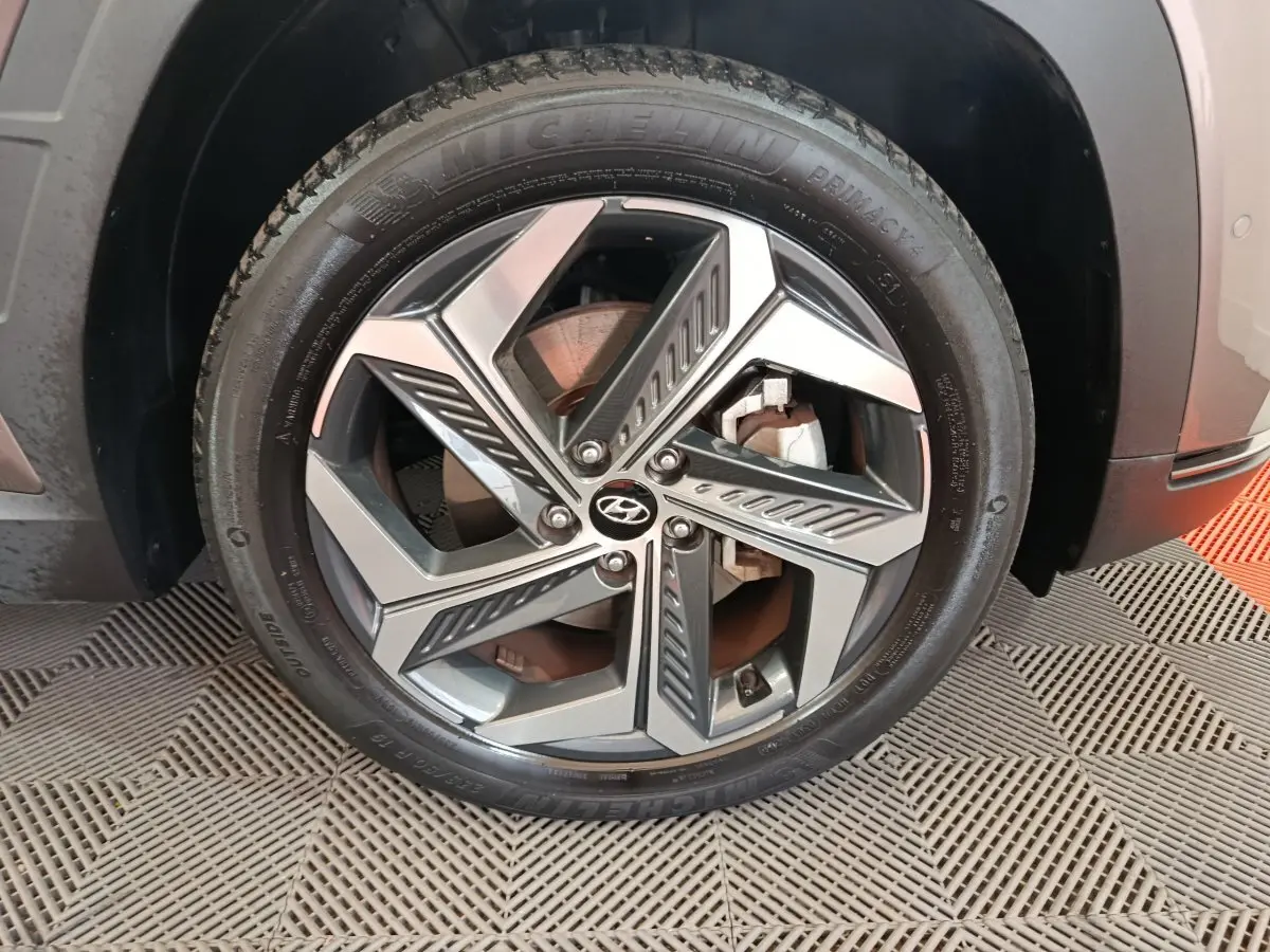 Gros plan sur la roue avant gauche du Hyundai Tucson marron, mettant en valeur la jante alliage au design moderne et le pneu Michelin.