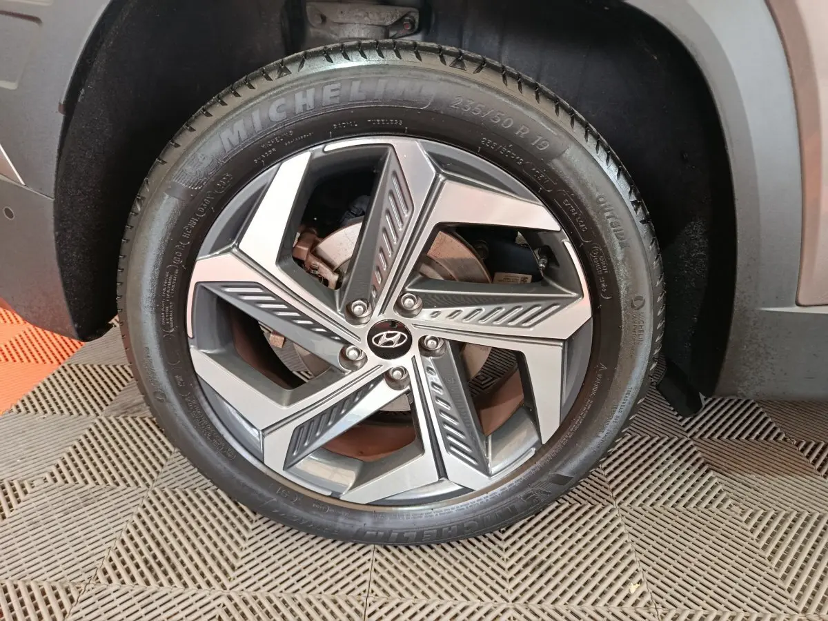 Gros plan sur la roue avant gauche du Hyundai Tucson marron, jante alliage moderne avec logo Hyundai central.