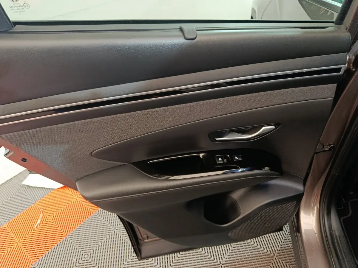 Gros plan sur la porte arrière gauche marron du Hyundai Tucson 2022 avec commandes de vitres et poignée argentée.