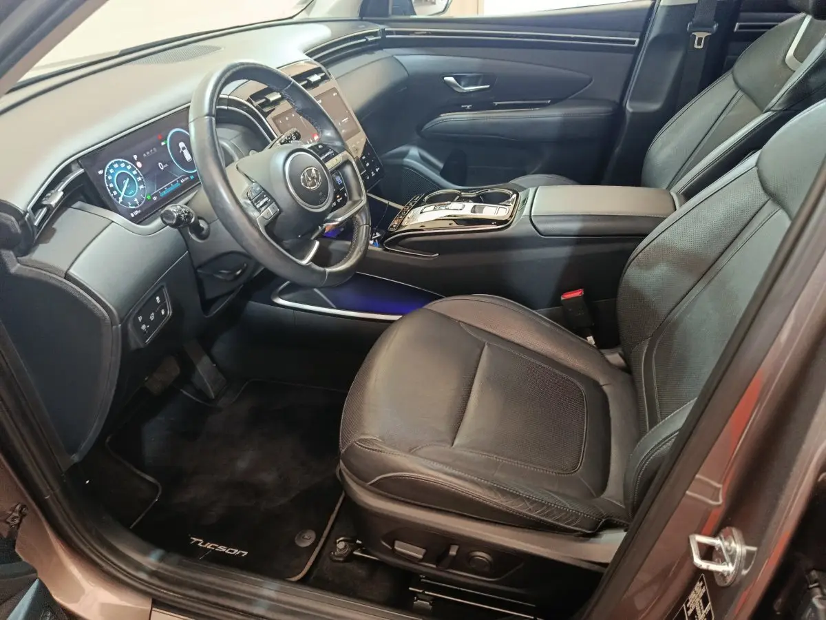 Intérieur avant droit du Hyundai Tucson marron 2022, avec tableau de bord digital et sièges cuir noirs.