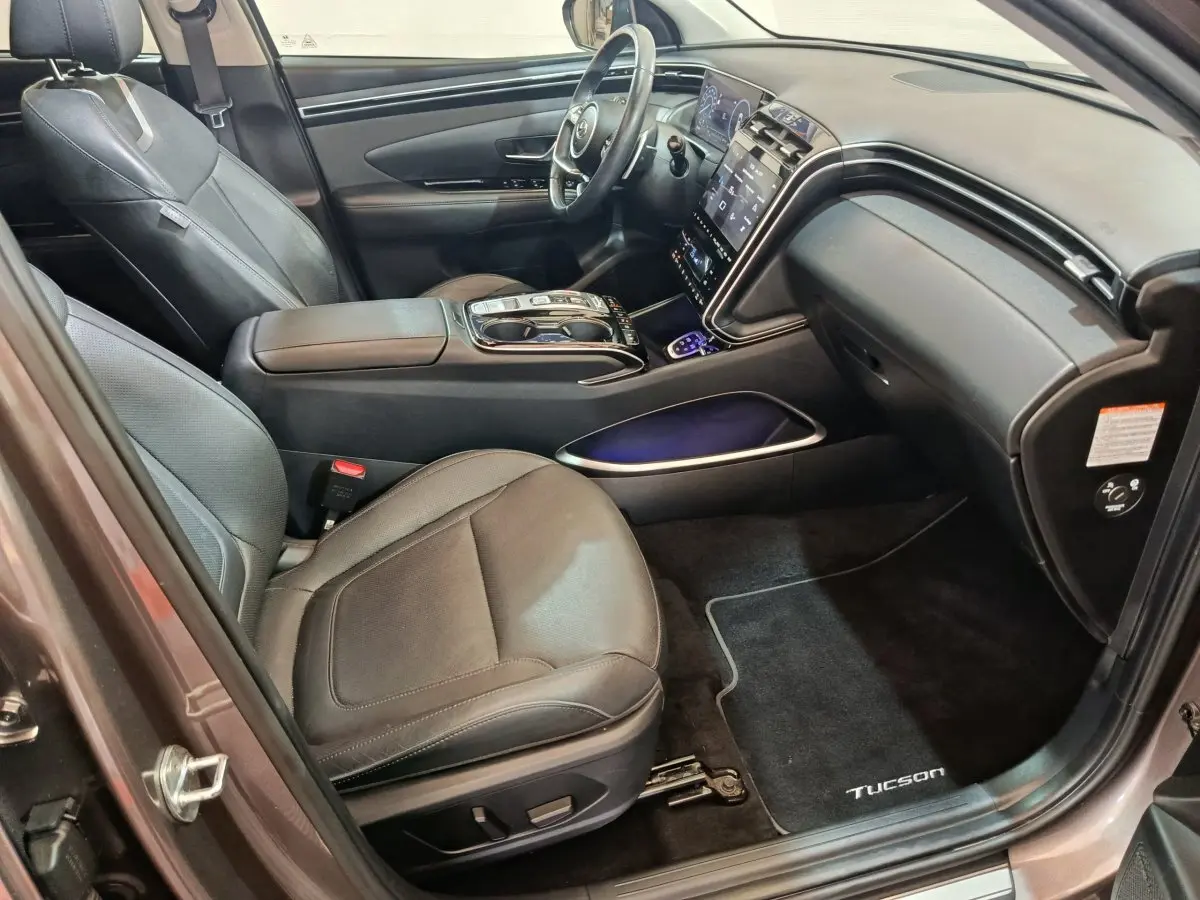 Intérieur avant droit du Hyundai Tucson marron 2022 avec sièges cuir noirs et grand écran tactile central.
