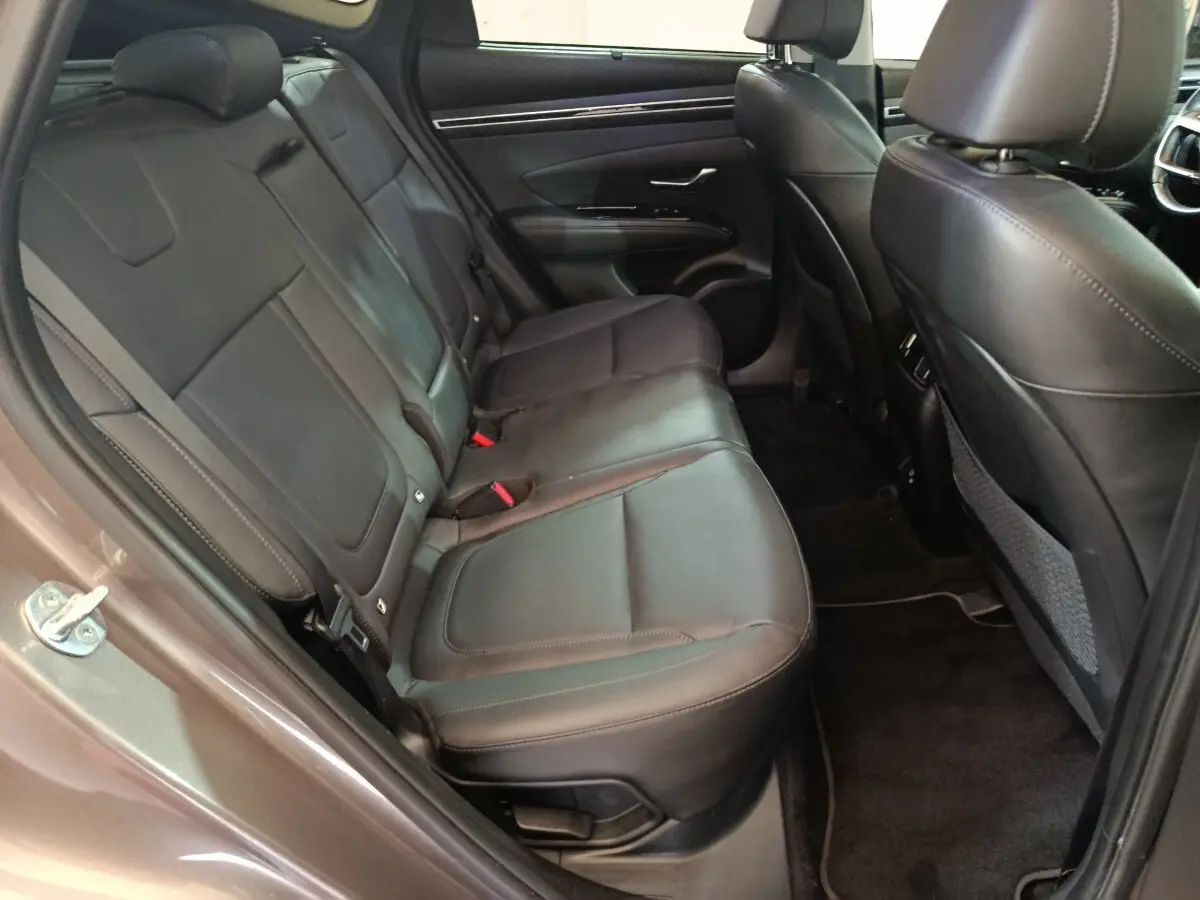 Vue côté gauche des sièges arrière en cuir noir du Hyundai Tucson 2022 marron, avec porte ouverte et intérieur spacieux.