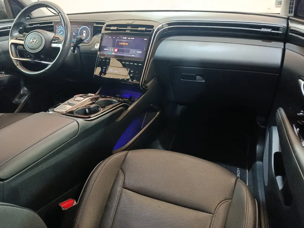 Vue intérieure côté passager du tableau de bord et console centrale noire du Hyundai Tucson 2022 hybride rechargeable.