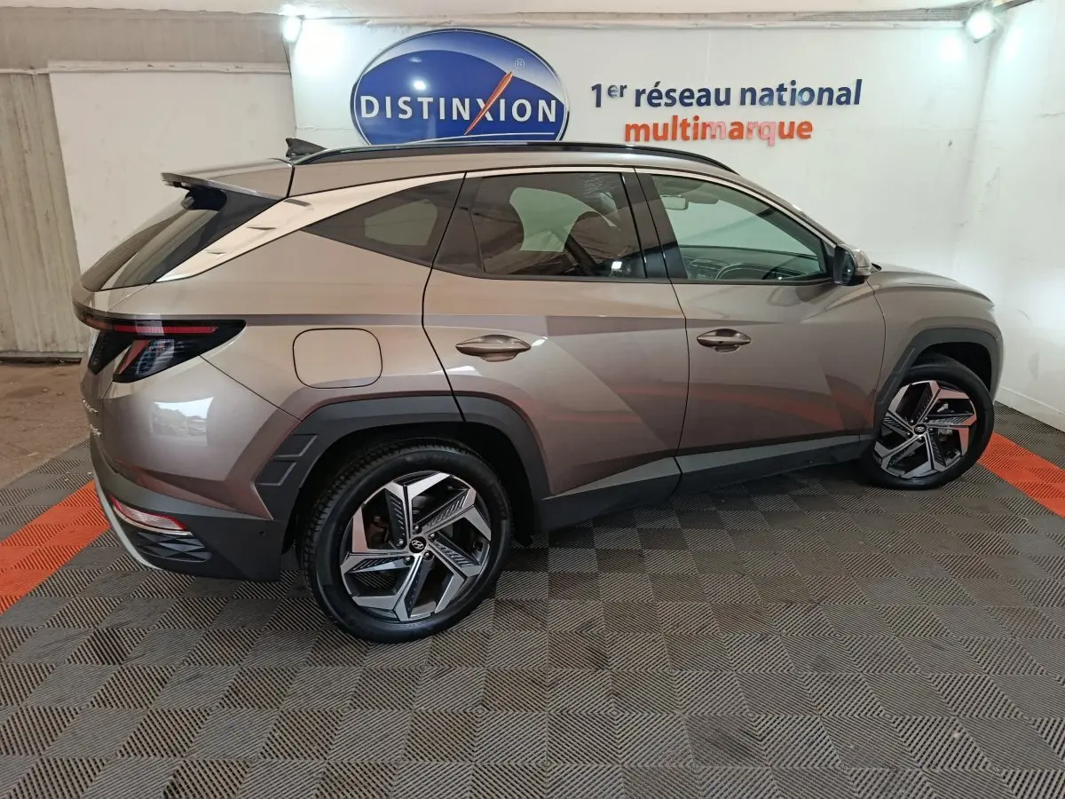 Vue latérale droite d'un Hyundai Tucson marron 2022 avec jantes alliage et toit ouvrant électrique en intérieur showroom.