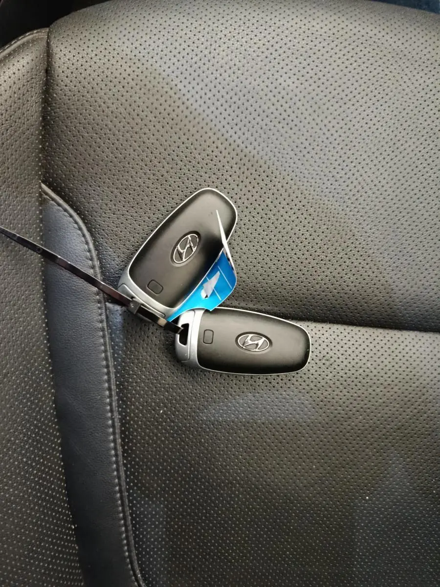 Gros plan sur deux clés Hyundai posées sur un siège en cuir perforé noir à l'intérieur du Tucson marron.