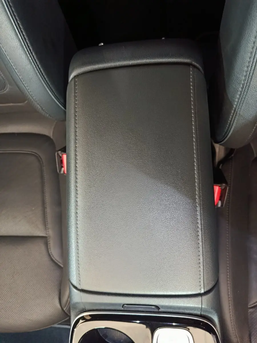 Vue plongeante sur l'accoudoir central en cuir noir entre les sièges avant du Hyundai Tucson marron 2022.