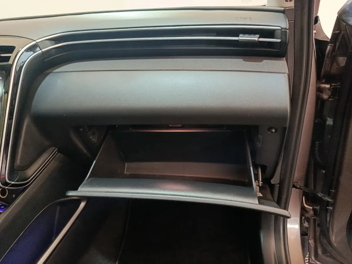 Intérieur du Hyundai Tucson 2022 marron, vue sur la boîte à gants ouverte côté passager avec tableau de bord noir.