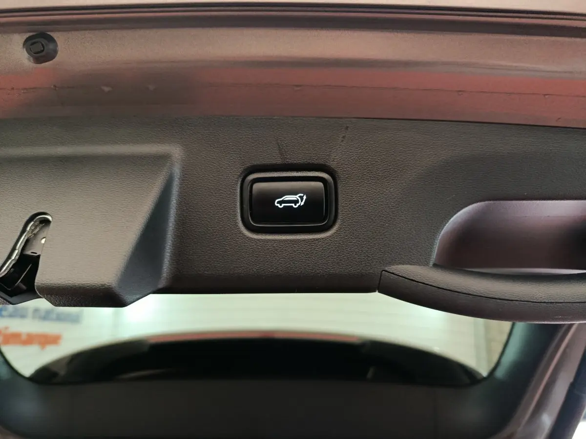 Bouton d'ouverture électrique du coffre sur la partie intérieure du hayon d'un Hyundai Tucson marron 2022.