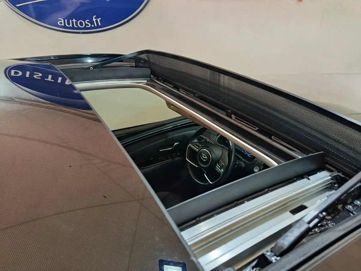 Vue rapprochée du toit ouvrant panoramique ouvert du Hyundai Tucson marron, montrant l'intérieur côté conducteur.