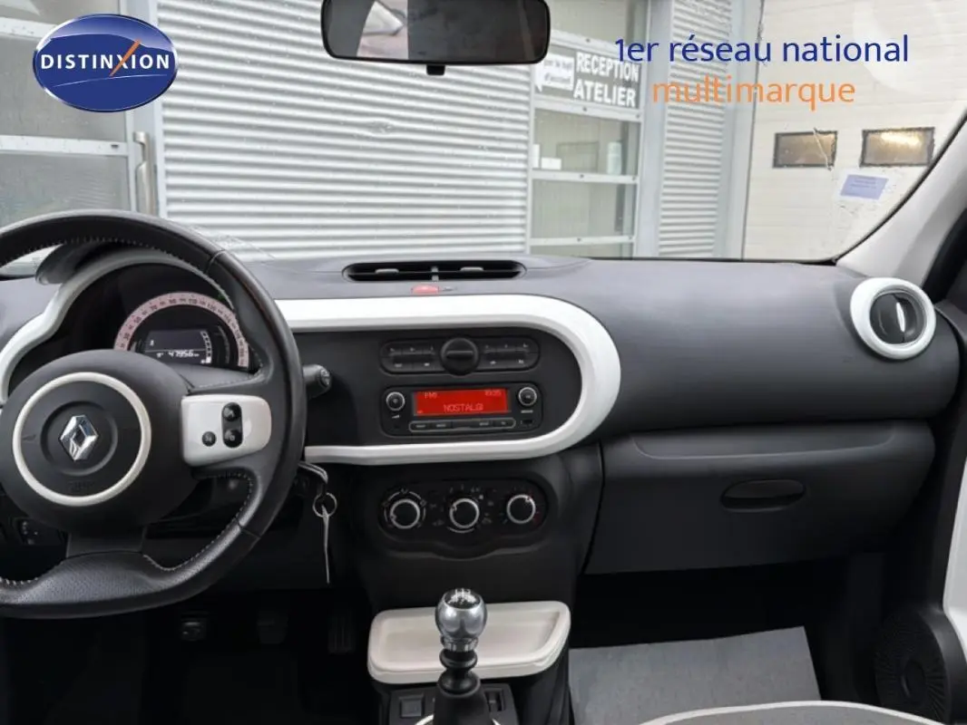 Vue intérieure du tableau de bord de la Renault Twingo III gris foncé, avec volant cuir et commande manuelle de vitesses.