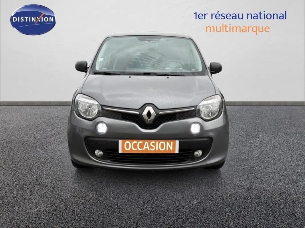 Vue frontale d'une Renault Twingo III gris foncé avec phares allumés et plaque "OCCASION" visible.