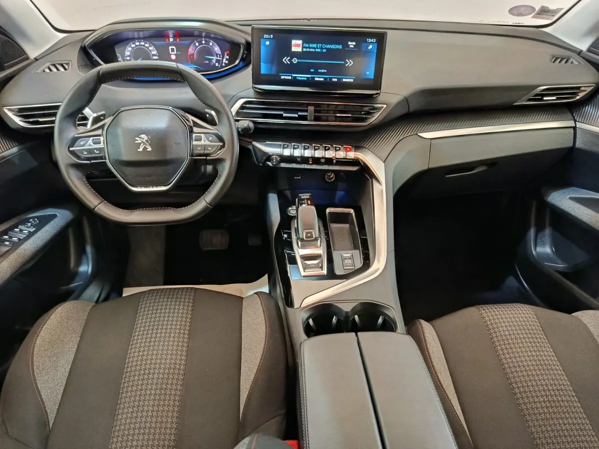 Vue intérieure avant du Peugeot 3008 gris foncé 2022, avec tableau de bord digital et écran tactile central lumineux.