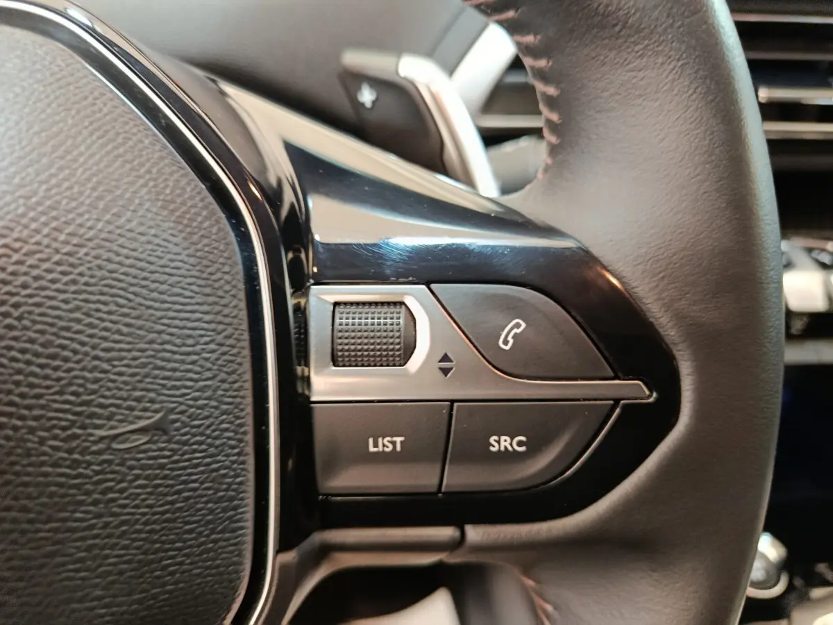 Gros plan sur les commandes multifonctions à gauche du volant cuir du Peugeot 3008 gris foncé, version 2022.