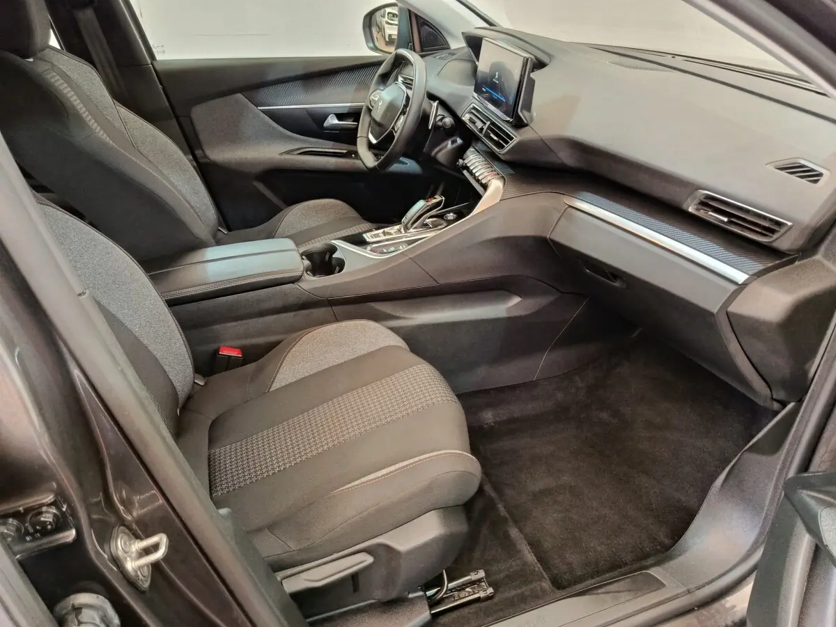 Vue intérieure côté passager avant du Peugeot 3008 gris foncé, avec tableau de bord digital et console centrale moderne.