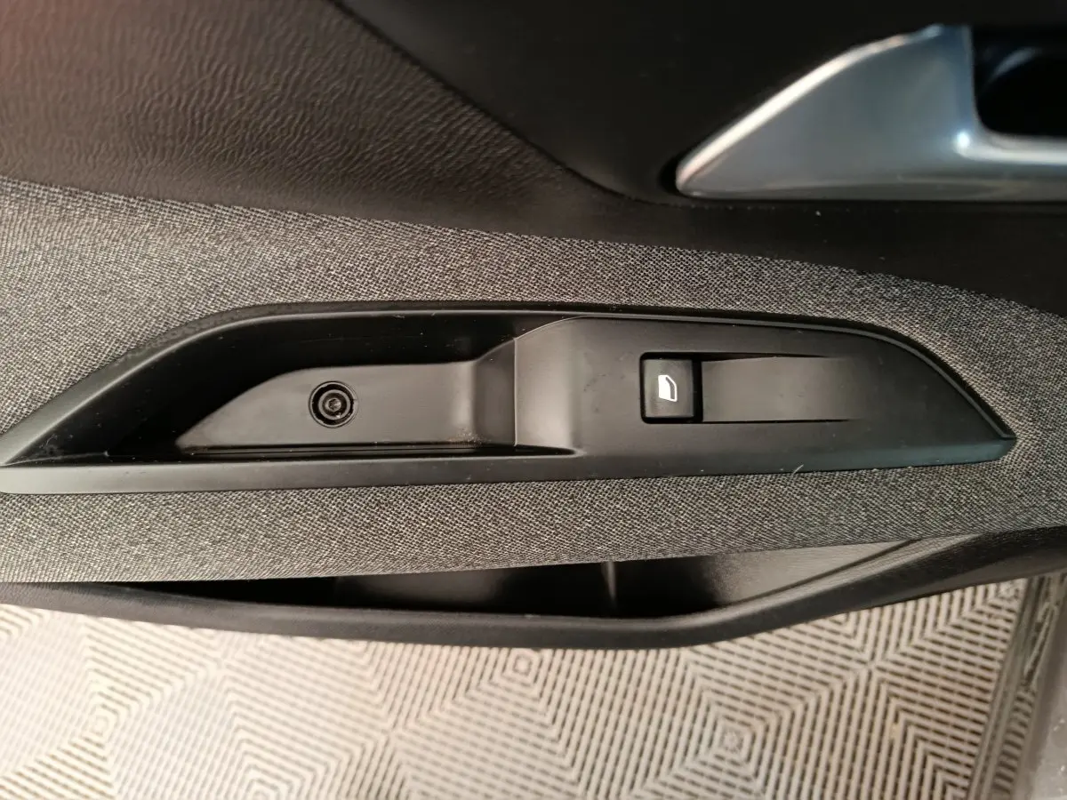 Détail de la commande d'ouverture de porte côté intérieur d'un Peugeot 3008 gris foncé, finition tissu.