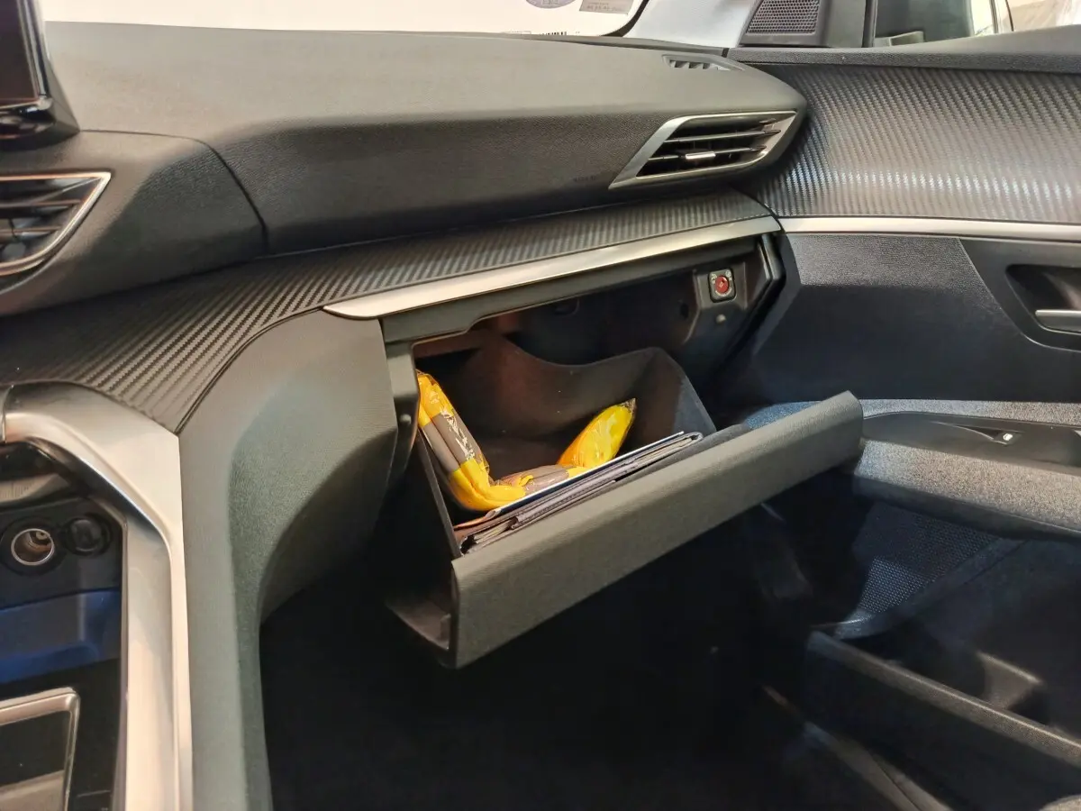 Intérieur côté passager du Peugeot 3008 gris foncé 2022, avec boîte à gants ouverte et tableau de bord texturé.