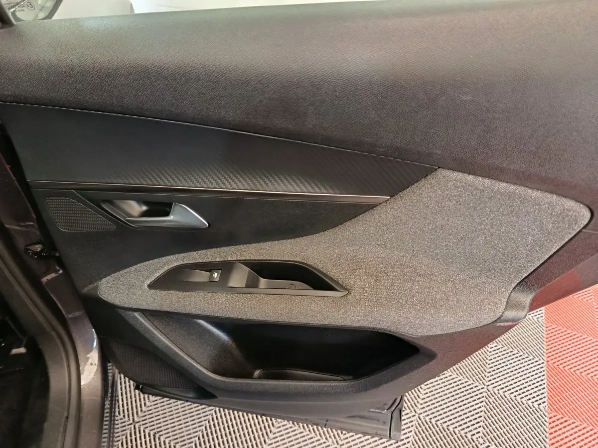 Vue côté gauche de la porte intérieure gris foncé du Peugeot 3008 avec insert tissu et commande de vitre.