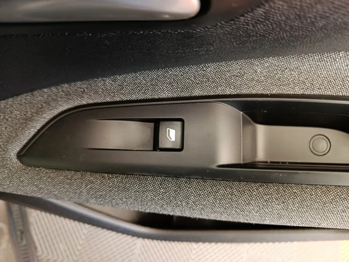 Gros plan sur la commande de lève-vitre côté passager intérieur du Peugeot 3008 gris foncé, tissu gris visible.