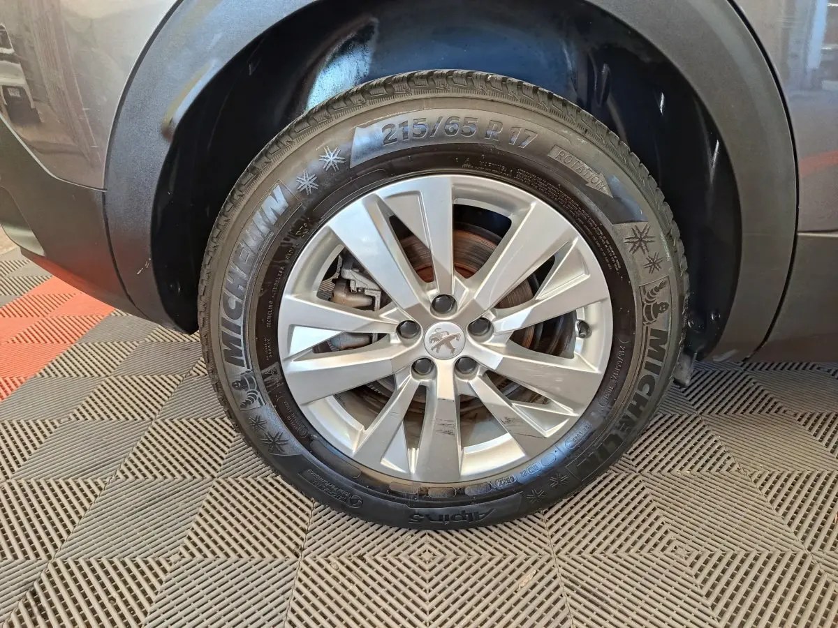 Gros plan sur la roue avant droite grise d’un Peugeot 3008 2022 avec jante alliage et pneu Michelin hiver.
