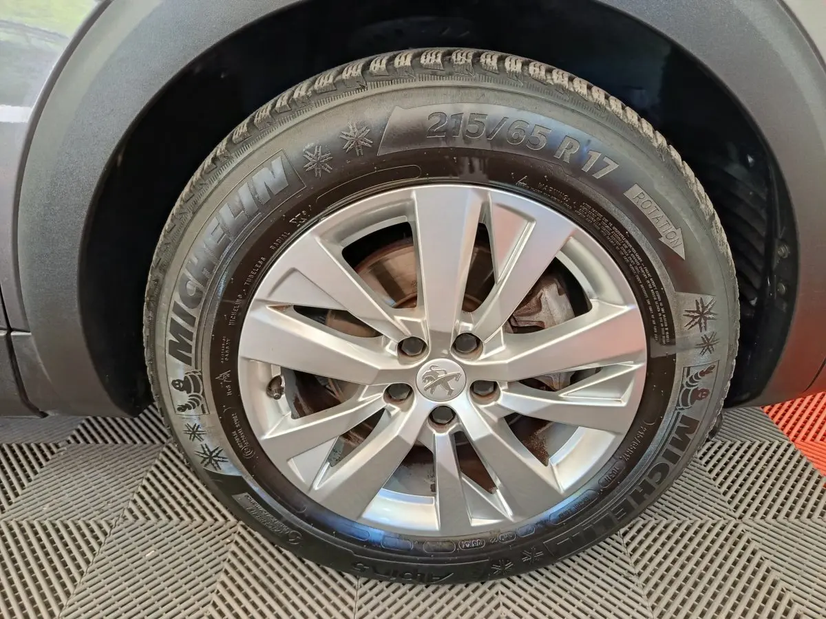 Gros plan sur la roue avant gauche d’un Peugeot 3008 gris foncé avec jante alliage et pneu Michelin hiver.