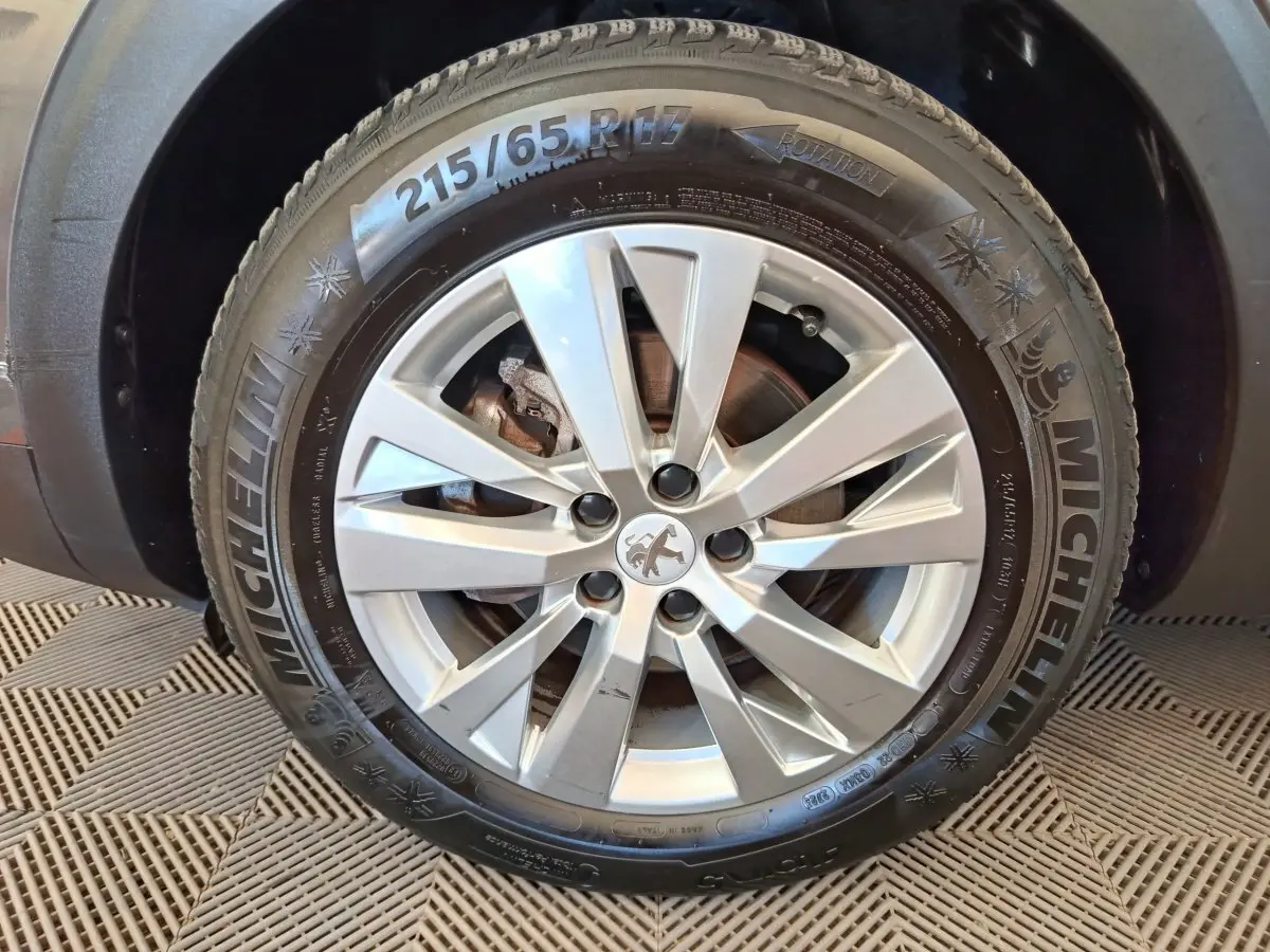 Gros plan sur la roue avant droite d’un Peugeot 3008 gris foncé avec jante alliage et pneu Michelin hiver.
