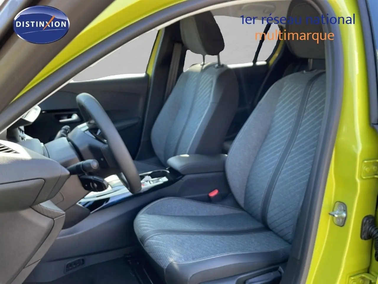 Vue intérieure côté conducteur de la Peugeot 208 Hybrid jaune Agueda, sièges tissu gris avec motifs diagonaux.