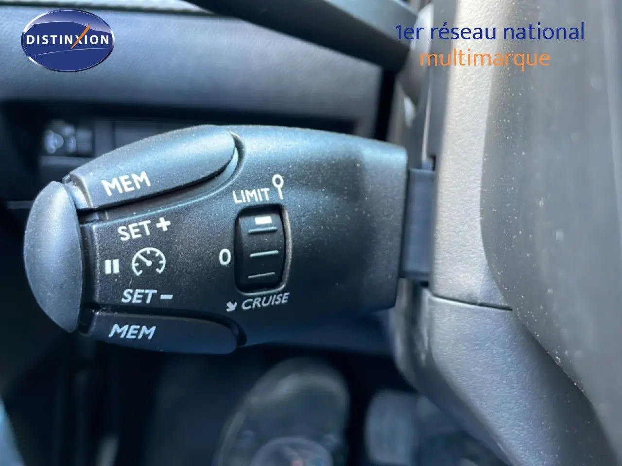 Gros plan sur la commande de régulateur de vitesse dans l'habitacle noir d'une Peugeot 208 jaune Agueda Metal.