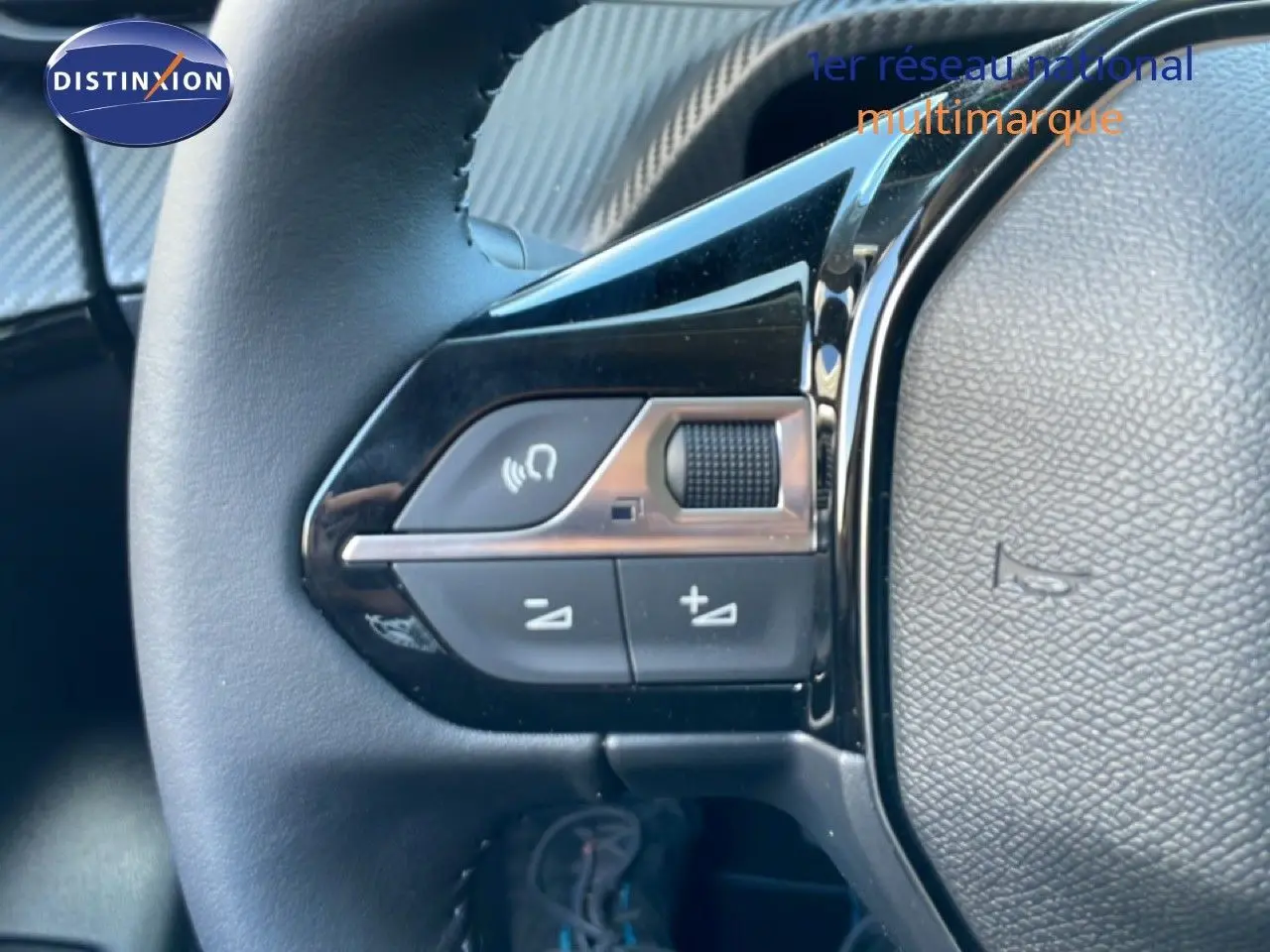 Gros plan sur les commandes de volume au volant d'une Peugeot 208 Hybrid jaune Agueda Metal, intérieur noir.