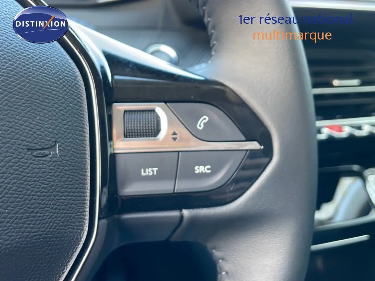 Gros plan sur les commandes gauche du volant en cuir noir d'une Peugeot 208 jaune Agueda Metal, version hybride 2026.