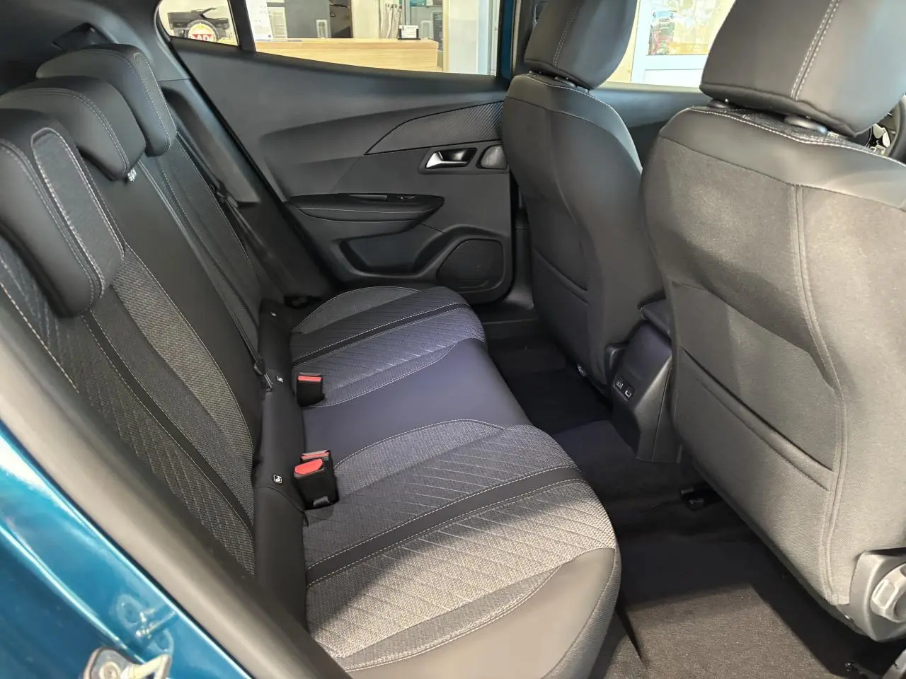 Vue intérieure arrière côté gauche du Peugeot 2008 bleu, montrant la banquette tissu/TEP avec surpiqûres Quartz et prises USB.
