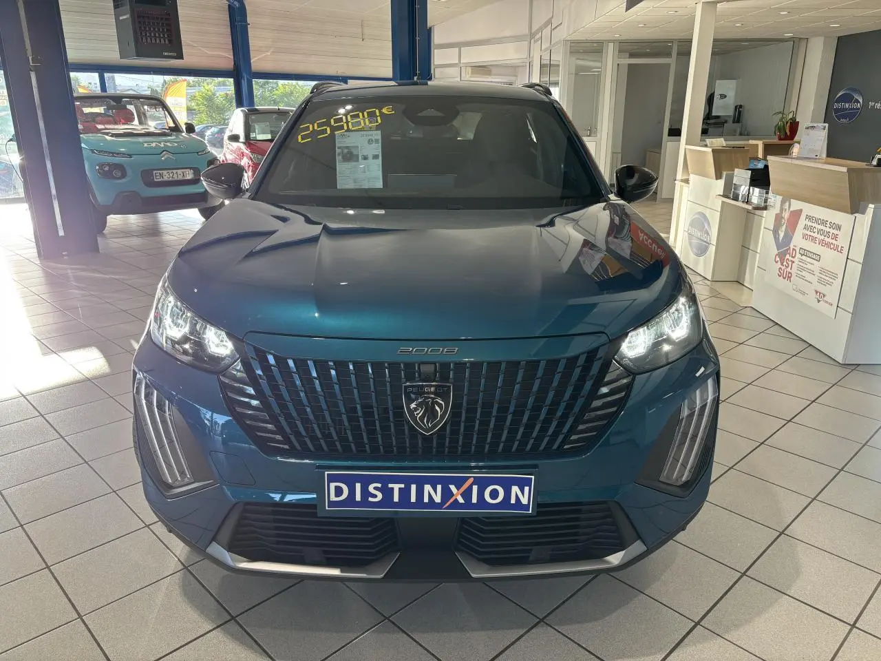 Vue avant d'un Peugeot 2008 bleu métallisé en showroom avec calandre noire et feux LED allumés.