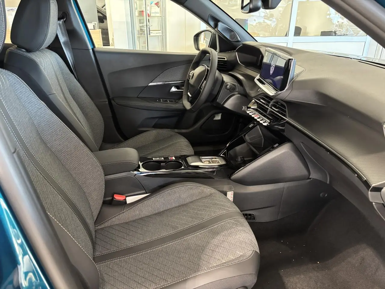 Vue intérieure côté conducteur du Peugeot 2008 bleu, avec sellerie tissu gris et tableau de bord moderne noir.