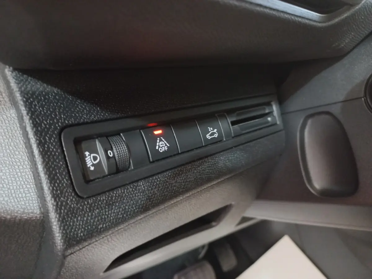 Gros plan sur les commandes d'éclairage et assistance au freinage du tableau de bord du Peugeot 5008 gris foncé, côté conducteur.