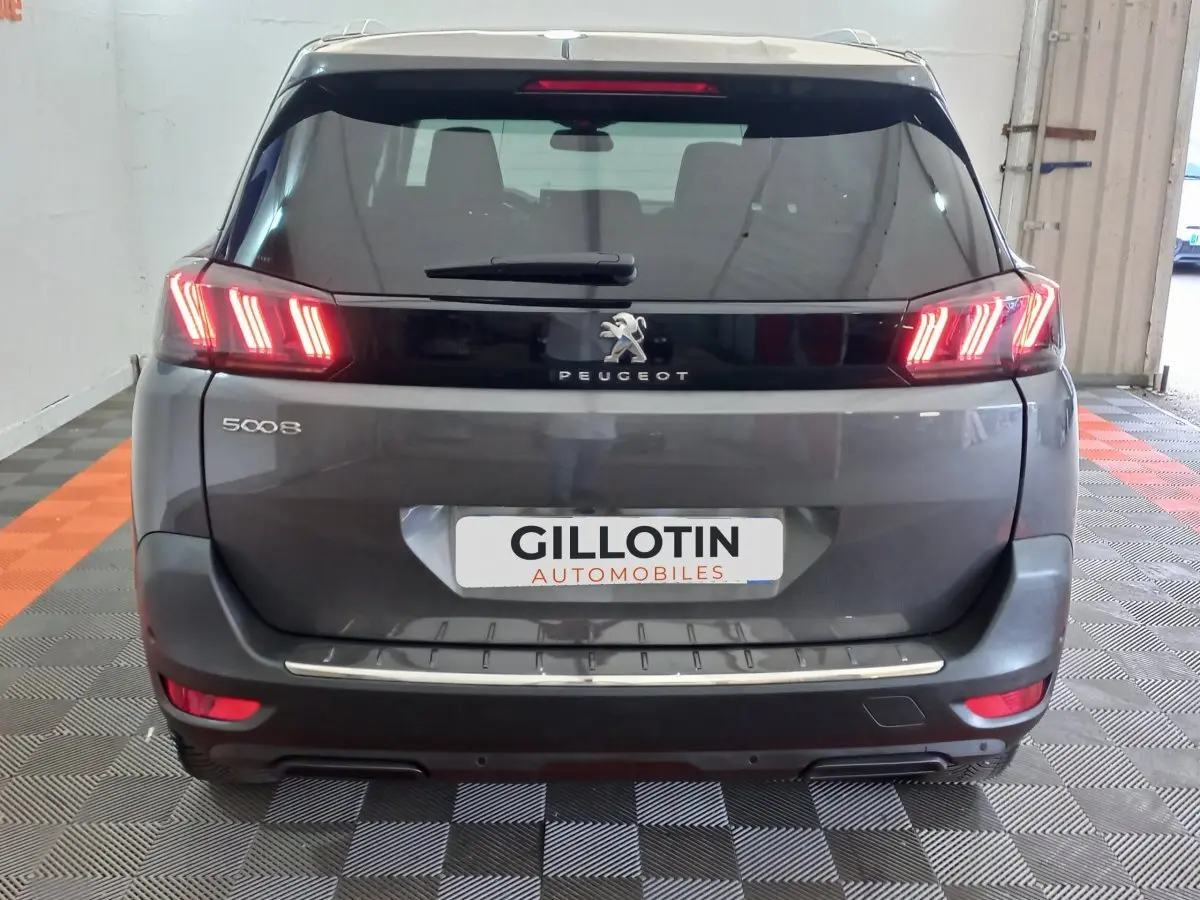 Vue arrière d'un Peugeot 5008 gris foncé avec feux LED caractéristiques et logo lion au centre du hayon.