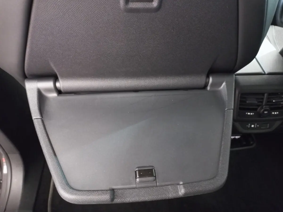 Gros plan sur la tablette rabattable noire du siège avant droit du Peugeot 5008 gris foncé, avec aérateurs arrière visibles.