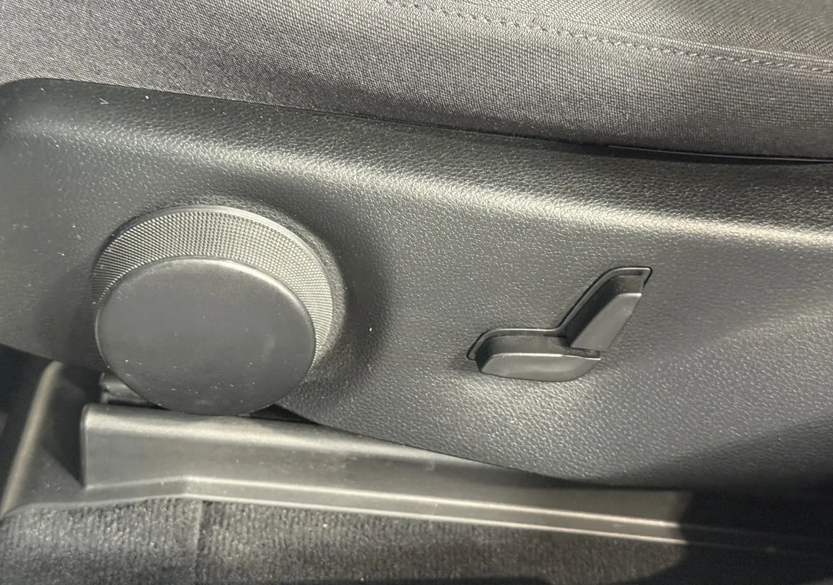 Gros plan sur les commandes de réglage manuel du siège côté conducteur du Mercedes GLK 220 cdi noir de 2010.