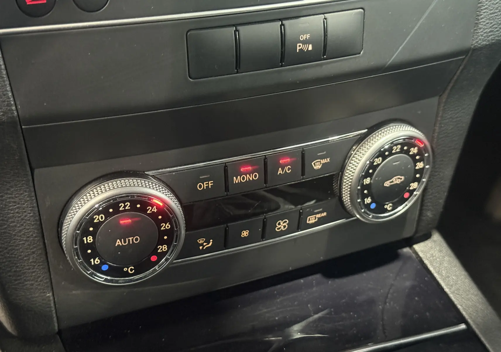 Gros plan sur la commande de climatisation automatique du Mercedes GLK noir 220 cdi Pack Sport, avec réglages numériques.