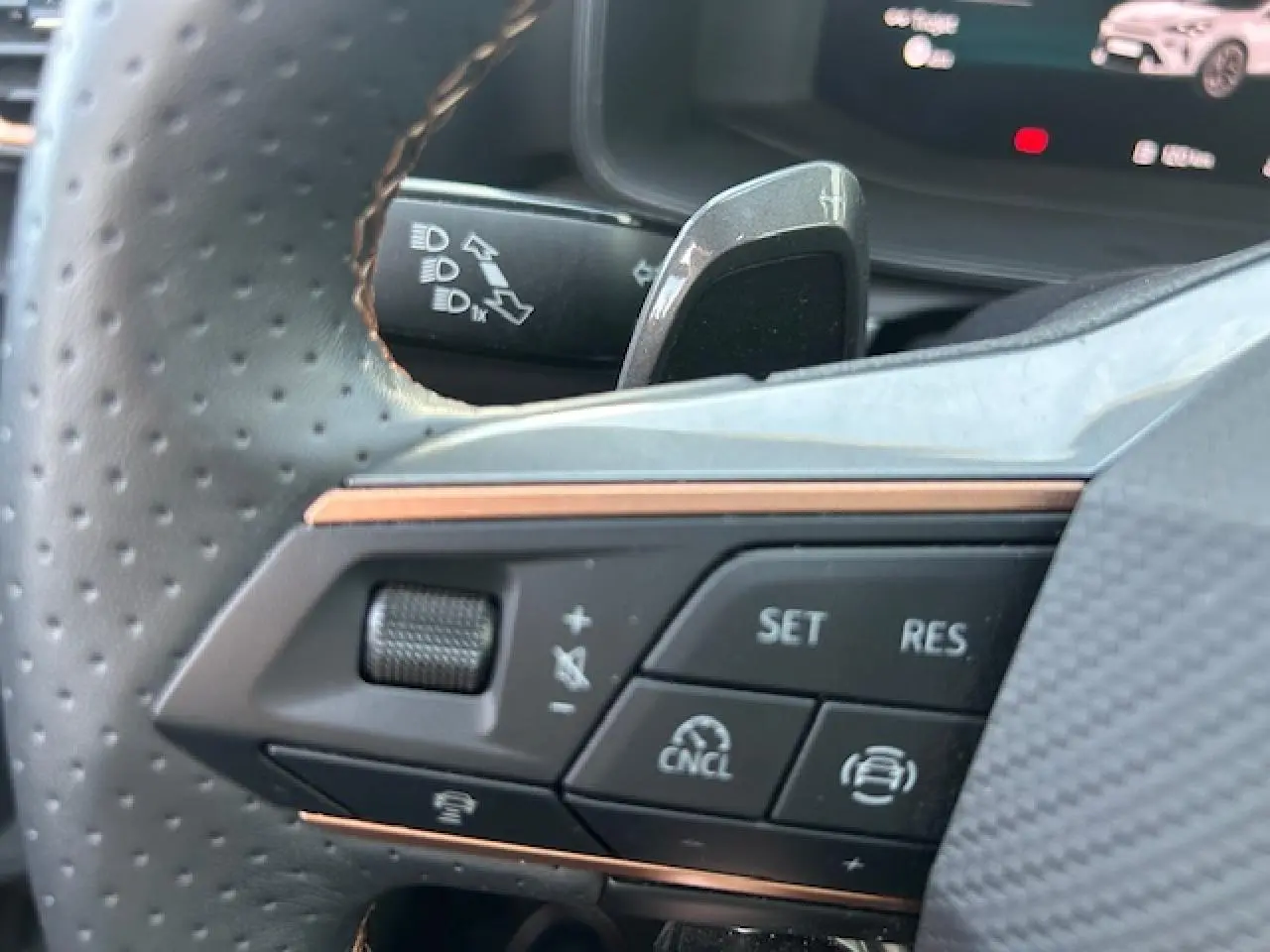 Gros plan sur les commandes au volant perforé du CUPRA Formentor blanc neige, avec palettes de changement de rapports visibles.