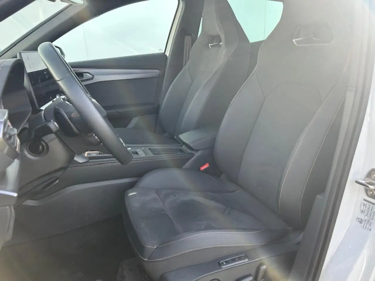 Vue intérieure côté conducteur du CUPRA Formentor blanc neige, sièges sport noirs avec surpiqûres contrastées et volant cuir.