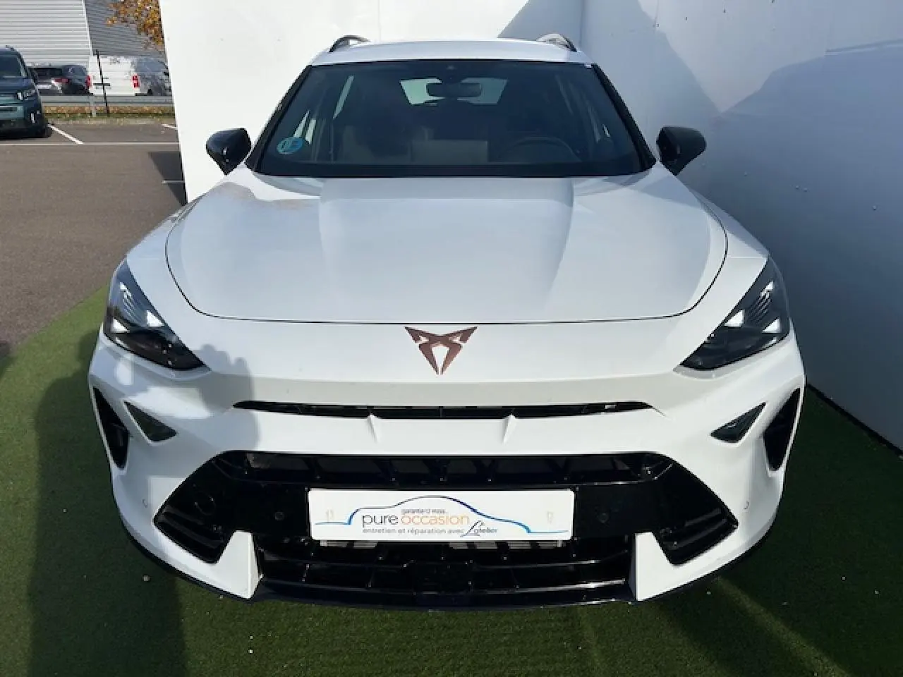 Vue de face d'un CUPRA Formentor blanc neige avec logo CUPRA cuivré et calandre noire brillante.