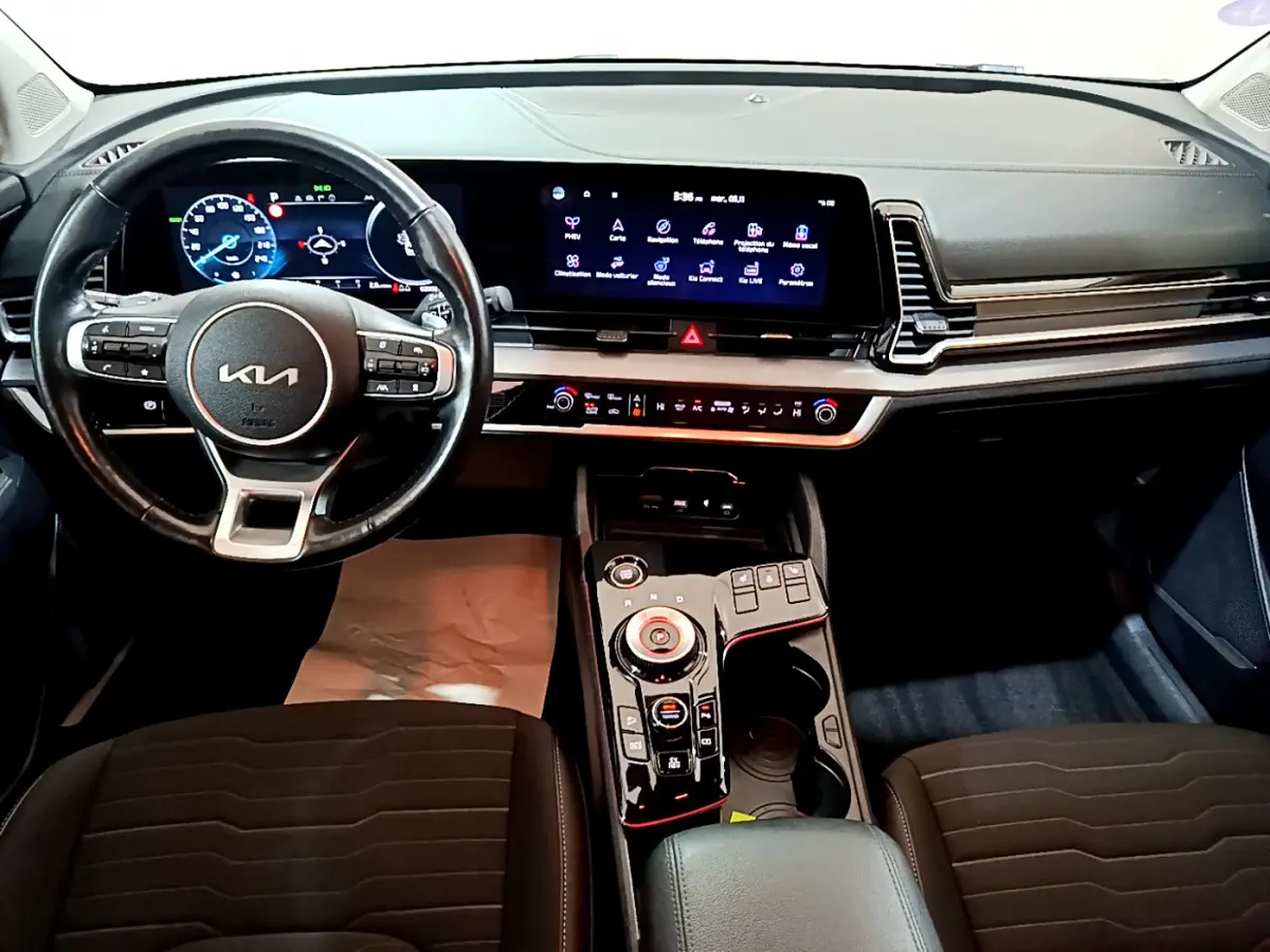 Vue intérieure frontale du tableau de bord et volant cuir noir du Kia Sportage hybride rechargeable 2022 avec écran tactile 12,3 pouces.