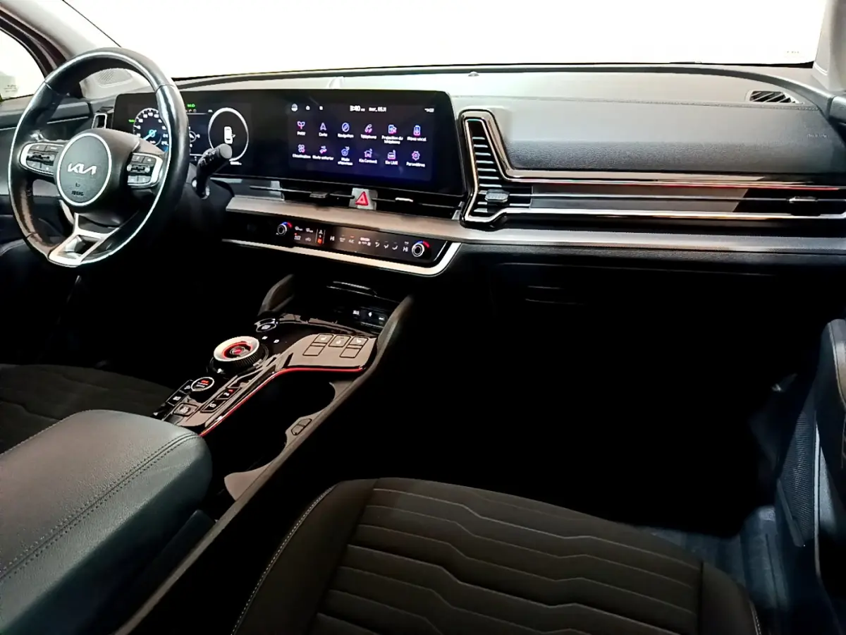 Vue intérieure côté conducteur du tableau de bord noir du Kia Sportage 2022 avec écran tactile et volant cuir multifonctions.