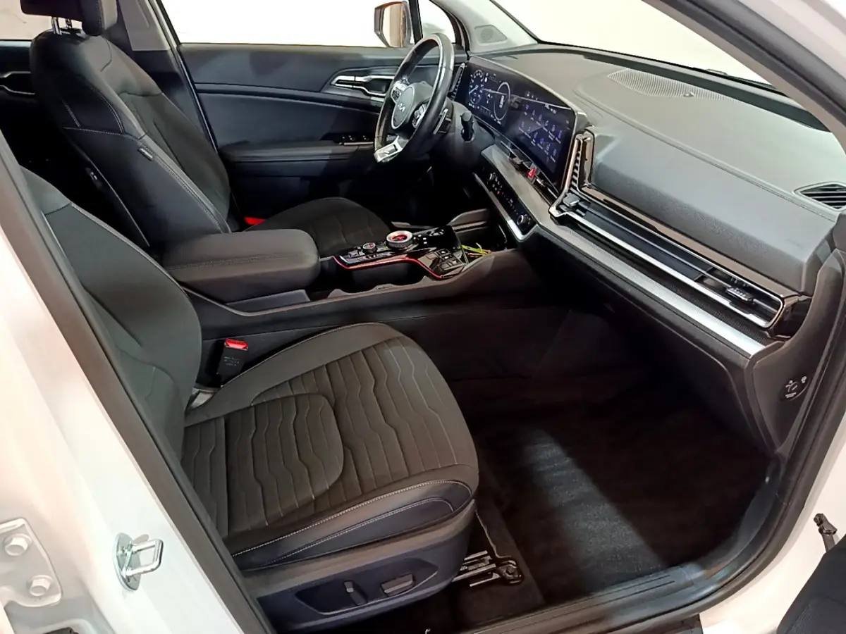 Intérieur avant droit du Kia Sportage blanc 2022, sièges noirs, tableau de bord digital et console centrale moderne.