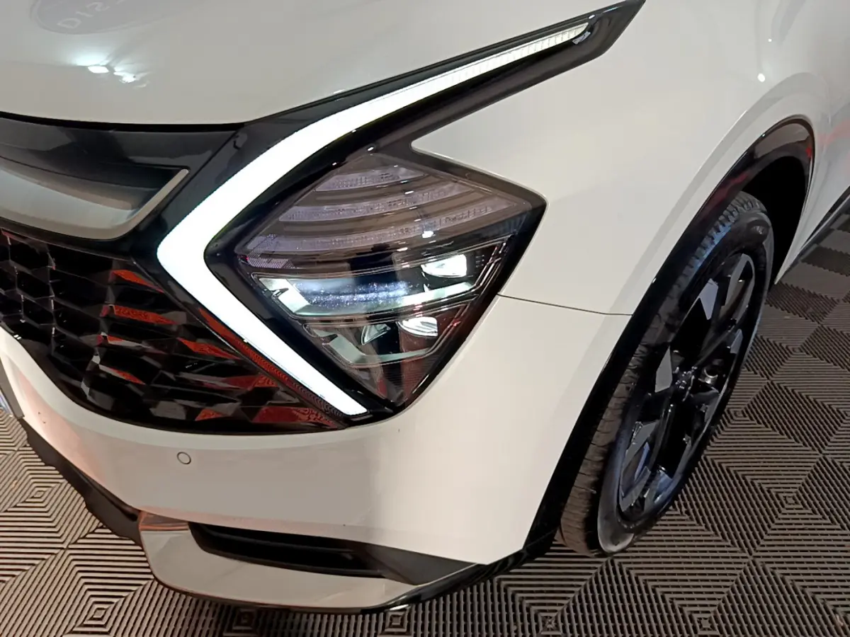 Gros plan sur le phare avant gauche blanc du Kia Sportage 2022 avec jante noire et éclairage LED distinctif.