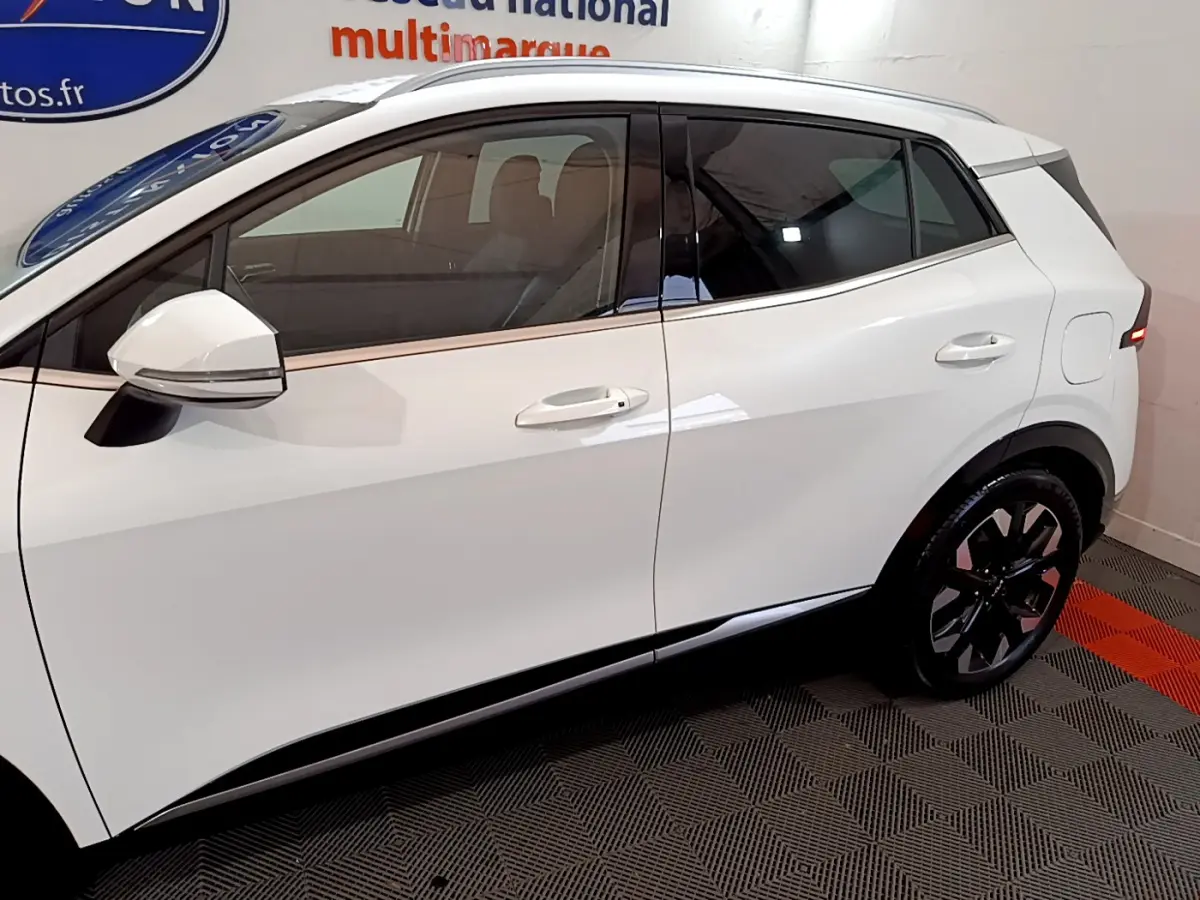 Vue latérale droite du KIA SPORTAGE blanc 2022 avec jantes noires et rétroviseurs blancs intégrant clignotants.