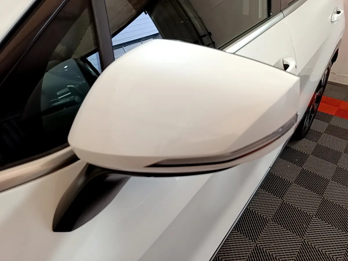 Rétroviseur blanc côté gauche du Kia Sportage 2022 hybride rechargeable, avec clignotant intégré et carrosserie blanche visible.