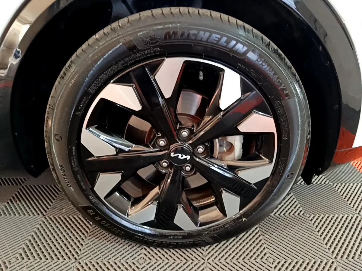 Gros plan sur la jante noire et argentée avec logo KIA du Kia Sportage blanc, mettant en valeur le pneu Michelin.