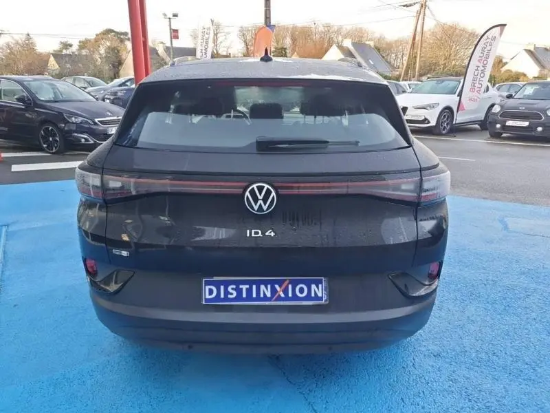 Vue arrière d'un Volkswagen ID.4 noir ébène métallisé, avec feux arrière LED reliés par une barre lumineuse rouge.